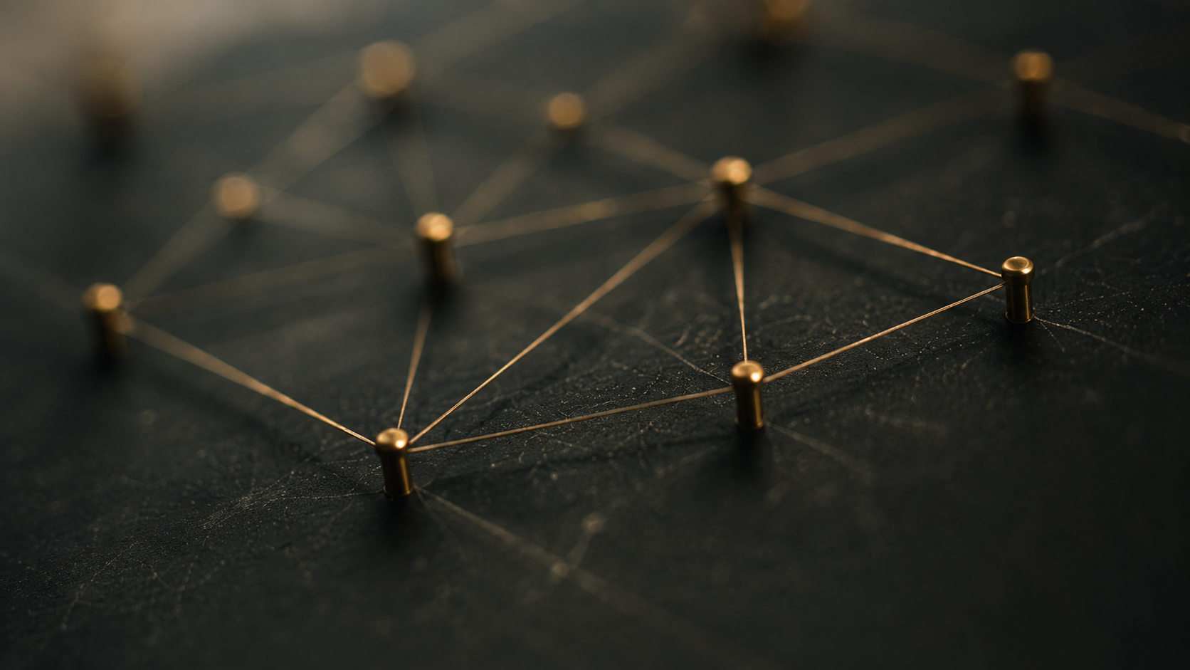 Brass pins connected by fine golden threads across a dark surface, forming a network map